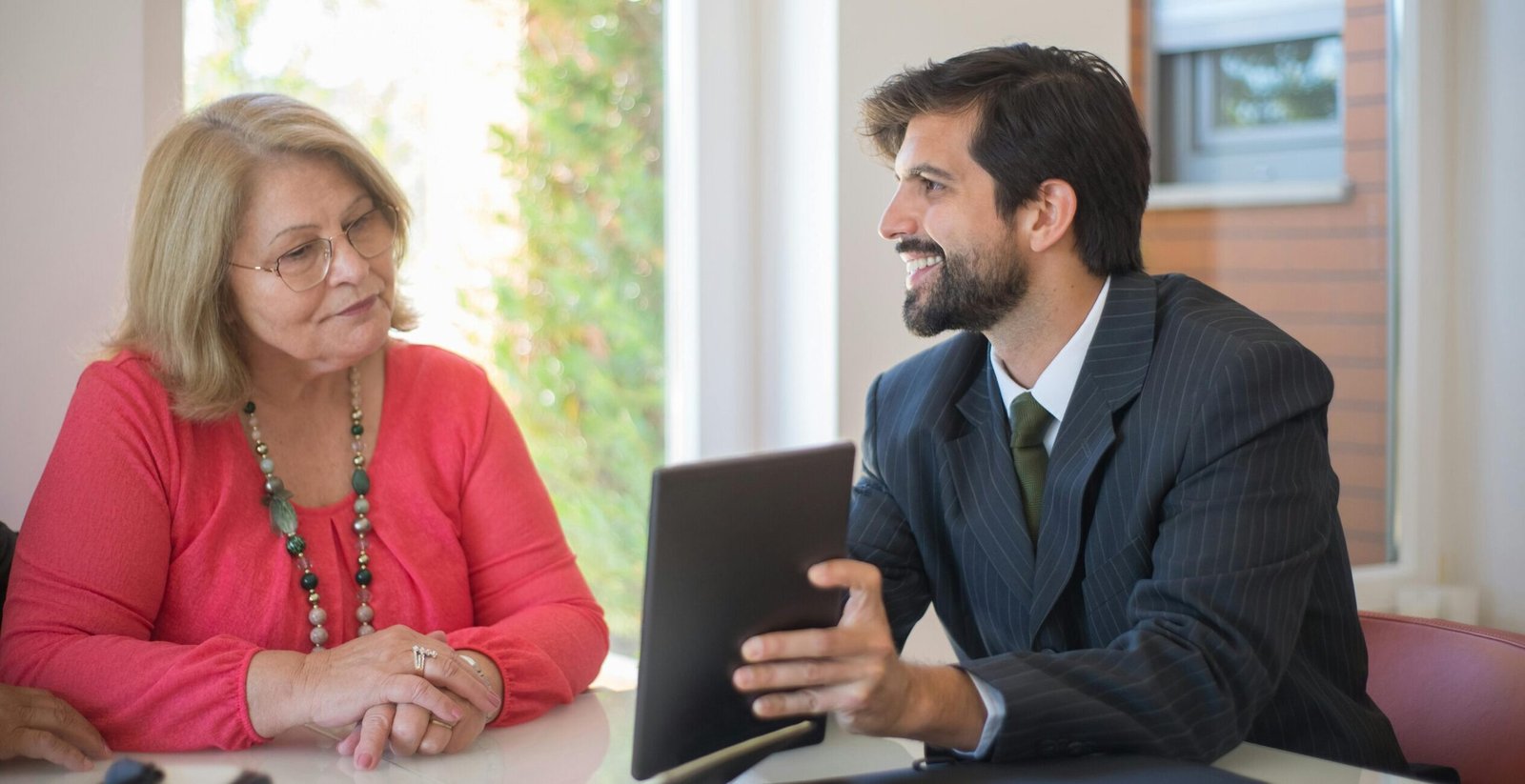 Elderly woman consulting with a realtor about a property deal in a cozy indoor setting.
